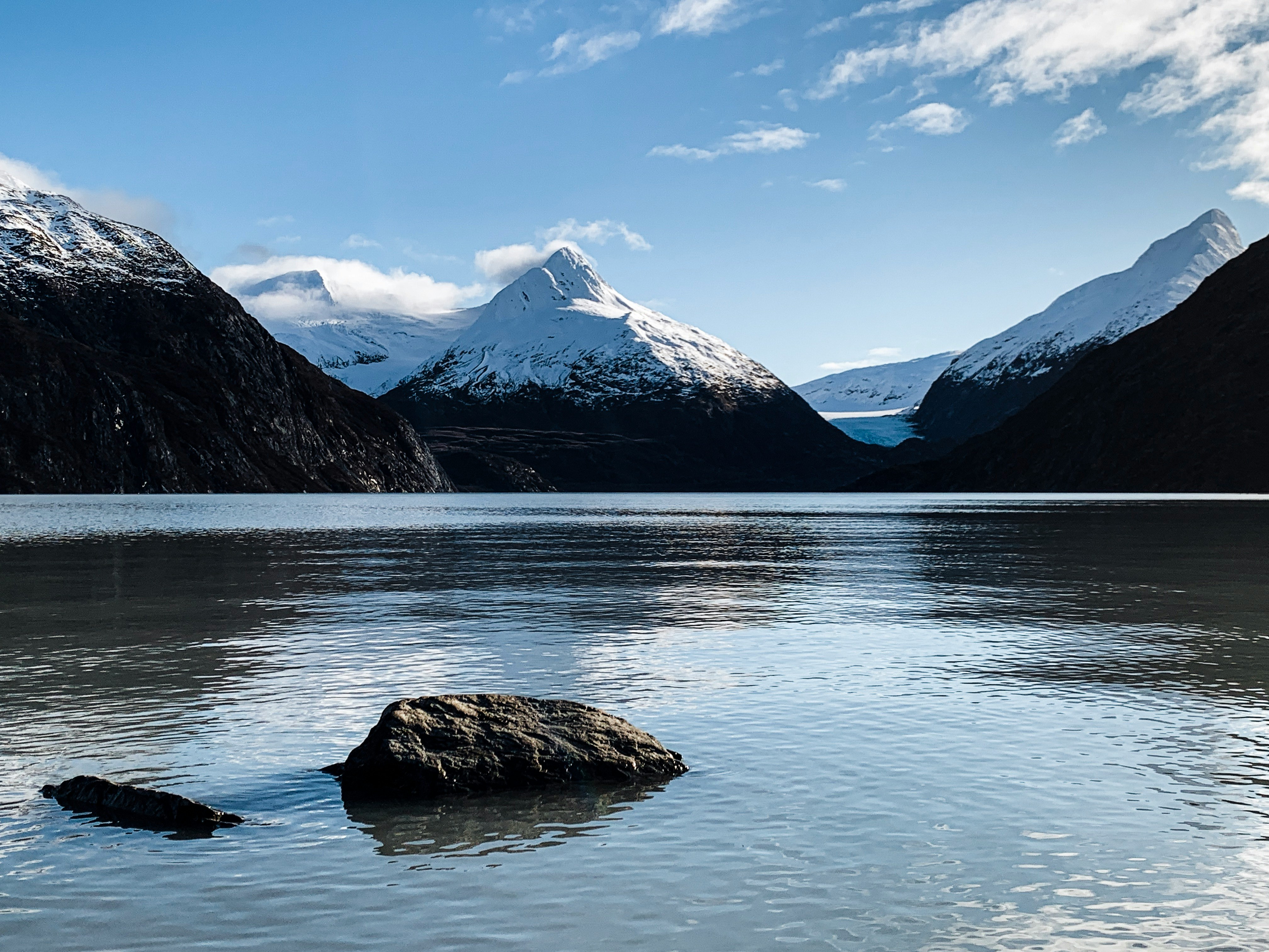 body of water near mountain under blue sky during daytime